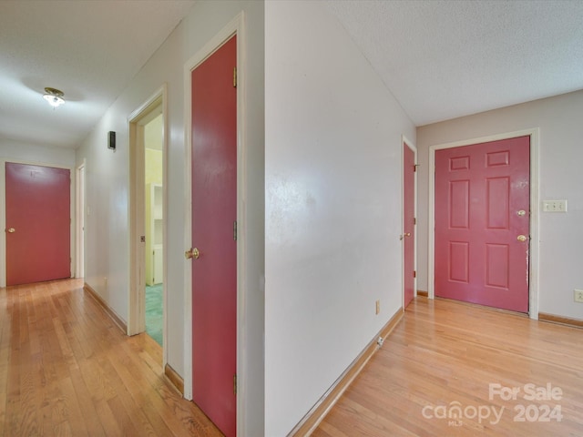 corridor featuring light hardwood / wood-style flooring and a textured ceiling