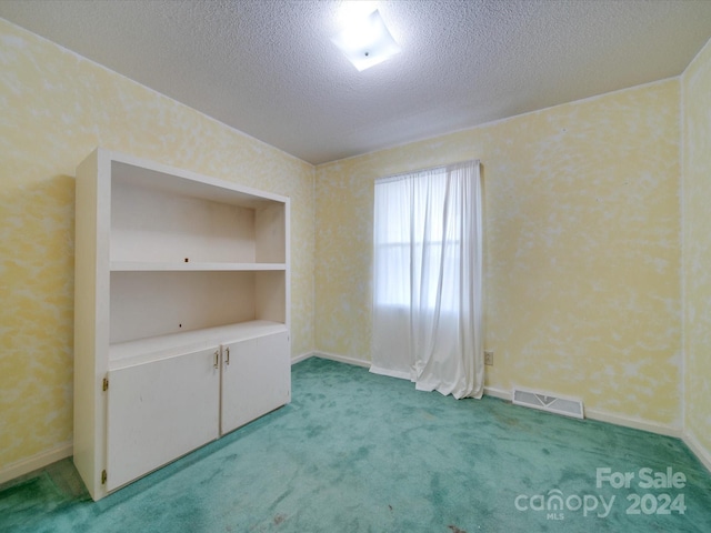 unfurnished room featuring a textured ceiling, carpet floors, and built in features