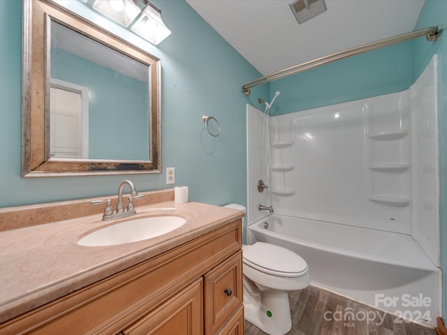 full bathroom with tub / shower combination, vanity, a textured ceiling, hardwood / wood-style floors, and toilet