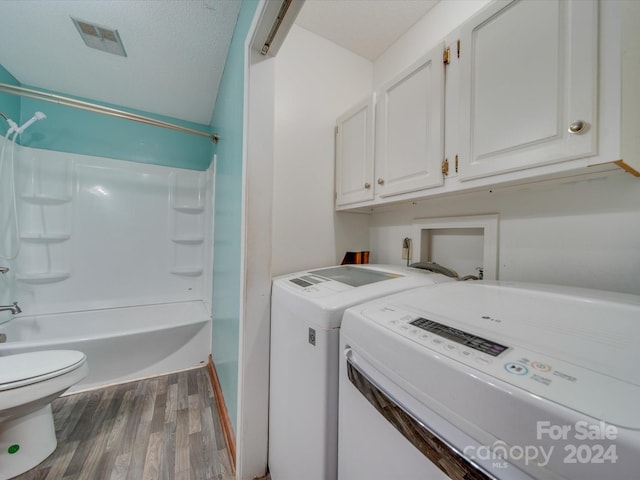 washroom with hardwood / wood-style floors, washing machine and dryer, and a textured ceiling