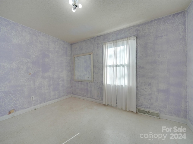 unfurnished room with a textured ceiling