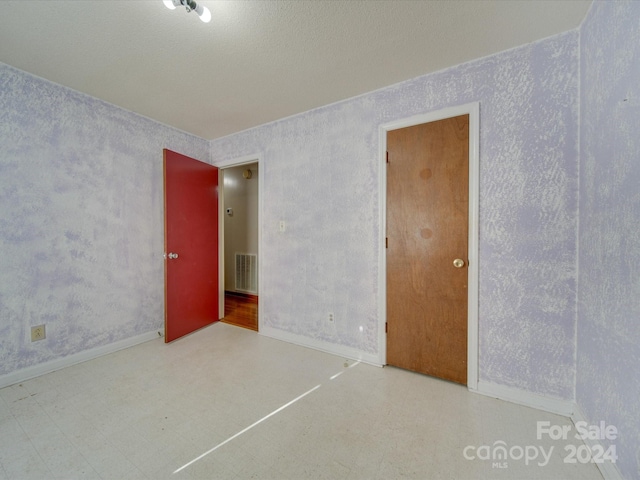 unfurnished room with a textured ceiling