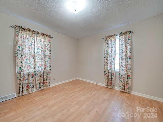 empty room featuring hardwood / wood-style flooring and a textured ceiling