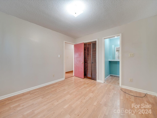 unfurnished bedroom featuring a closet, light hardwood / wood-style floors, and a textured ceiling