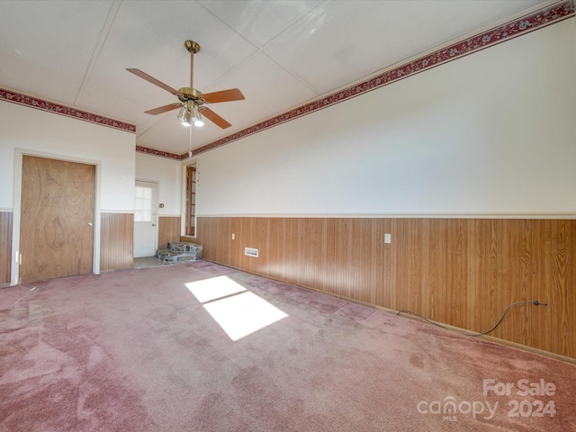 unfurnished living room featuring carpet, ceiling fan, and wood walls