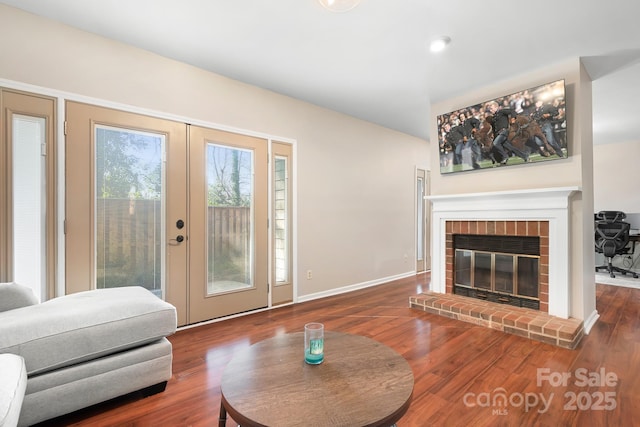 living room featuring a brick fireplace, hardwood / wood-style flooring, and french doors