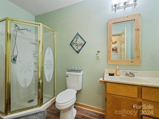 bathroom with wood-type flooring, a textured ceiling, toilet, and a shower with door