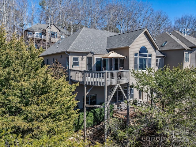 rear view of house featuring a deck and roof with shingles