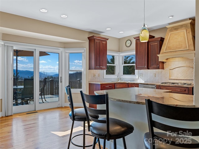 20 Red Plum Ln, Black Mountain, NC 28711 - kitchen featuring a breakfast bar, appliances with stainless steel finishes, light stone countertops, light wood finished floors, and custom range hood