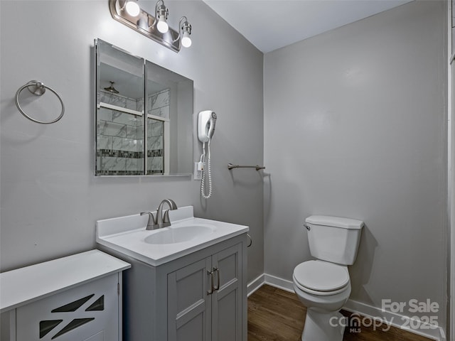 bathroom featuring vanity, a shower, hardwood / wood-style floors, and toilet