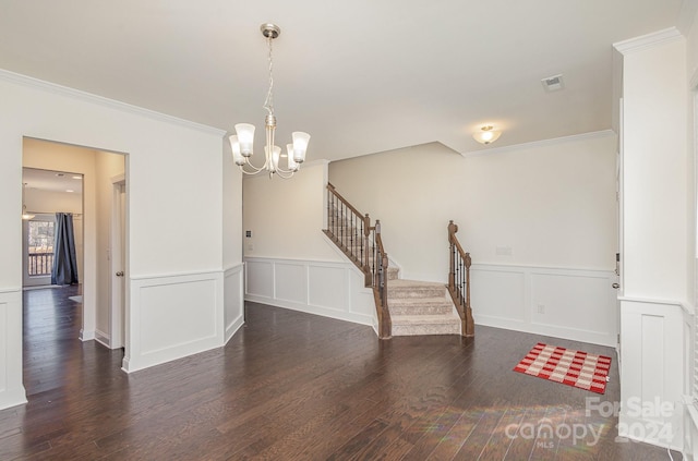 spare room featuring ornamental molding, dark wood-type flooring, and a chandelier