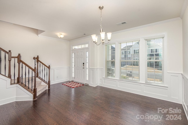 entryway with dark hardwood / wood-style floors, crown molding, and an inviting chandelier