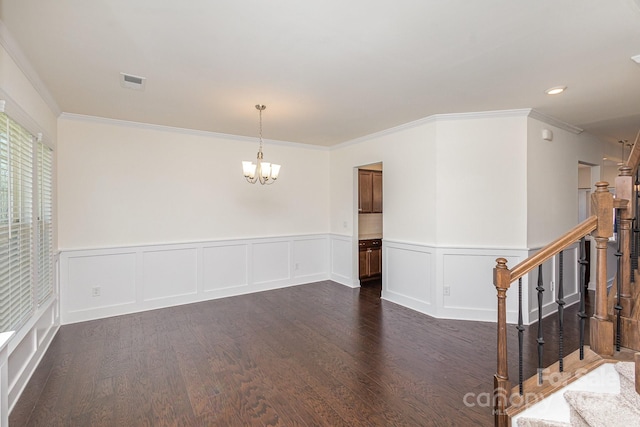 empty room featuring a chandelier, crown molding, and dark wood-type flooring