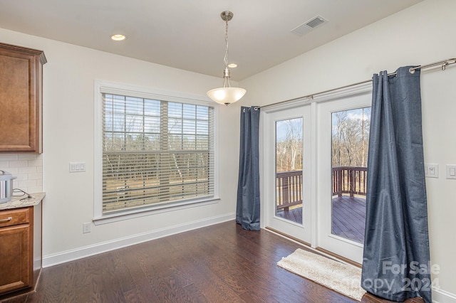 unfurnished dining area featuring plenty of natural light and dark hardwood / wood-style floors