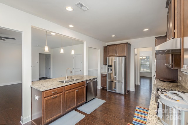 kitchen with sink, tasteful backsplash, light stone counters, dark hardwood / wood-style flooring, and appliances with stainless steel finishes