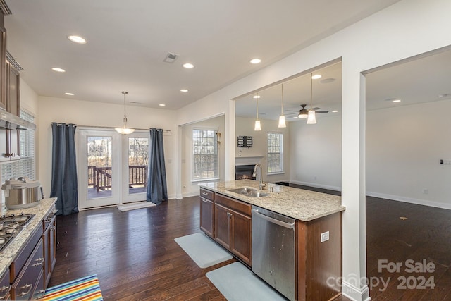 kitchen with light stone counters, stainless steel appliances, dark wood-type flooring, sink, and pendant lighting