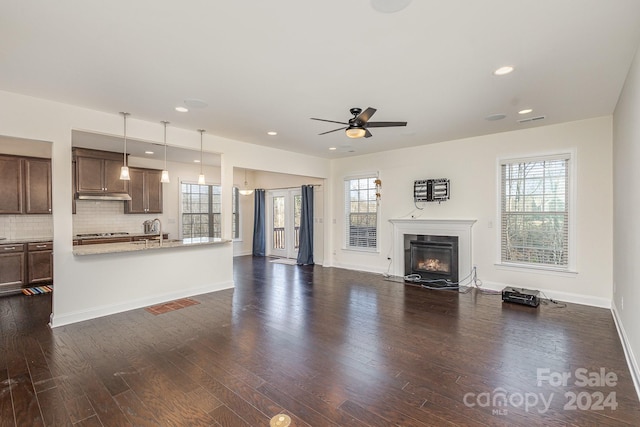 unfurnished living room with ceiling fan, a healthy amount of sunlight, and dark hardwood / wood-style flooring