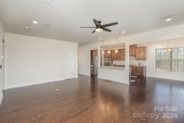 unfurnished living room featuring ceiling fan with notable chandelier, dark hardwood / wood-style flooring, and sink