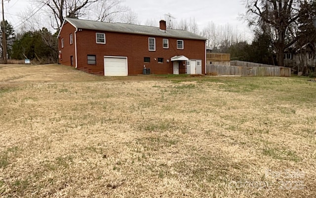 back of house with central AC unit, a garage, and a yard