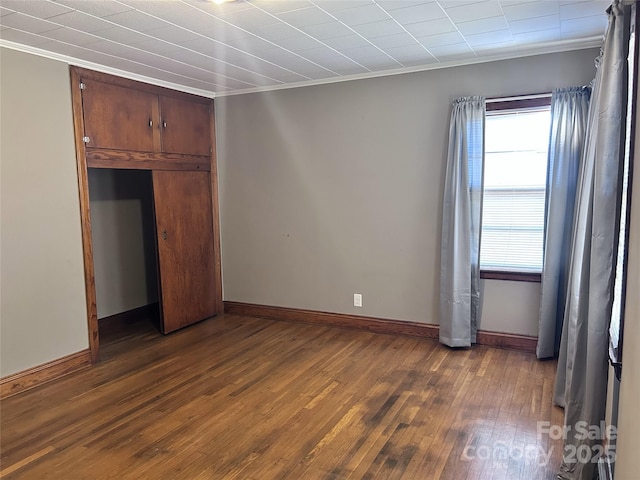 unfurnished bedroom featuring a closet, dark hardwood / wood-style floors, and ornamental molding