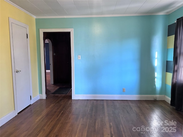 spare room featuring dark wood-type flooring and crown molding