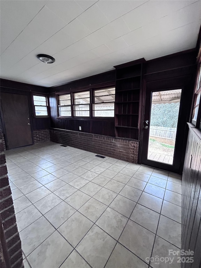 tiled foyer featuring brick wall