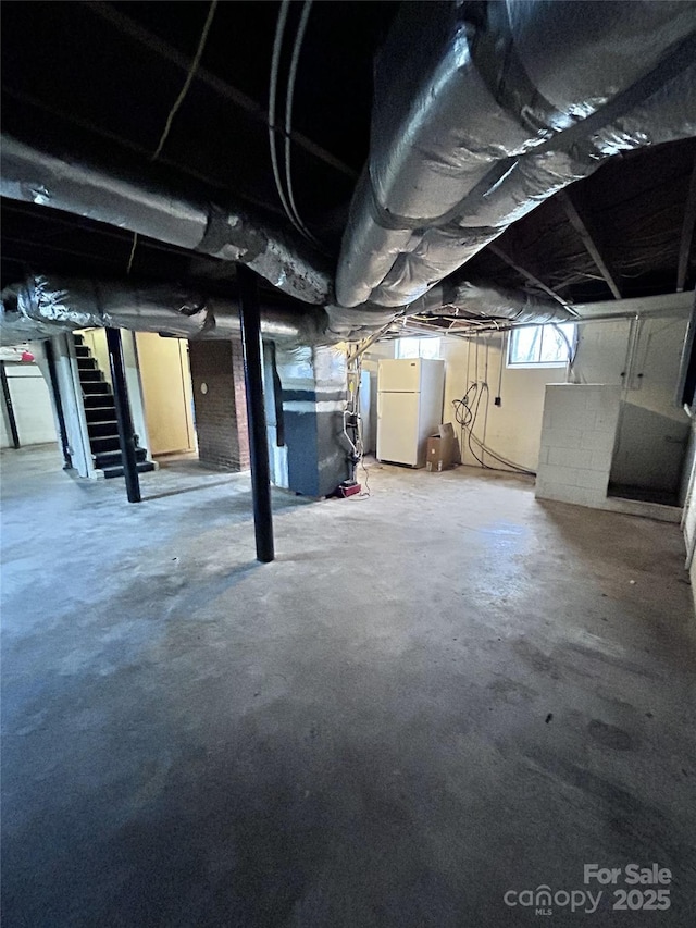 basement featuring heating unit and white refrigerator