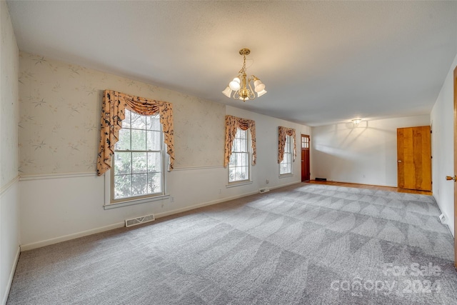 unfurnished room featuring a notable chandelier and light colored carpet