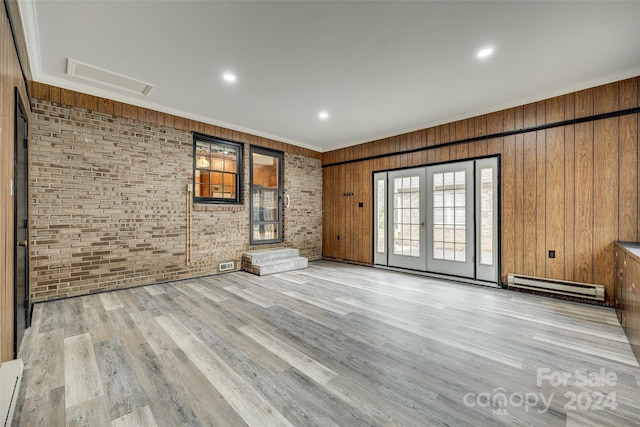 unfurnished living room with ornamental molding, light hardwood / wood-style flooring, wooden walls, and a baseboard heating unit