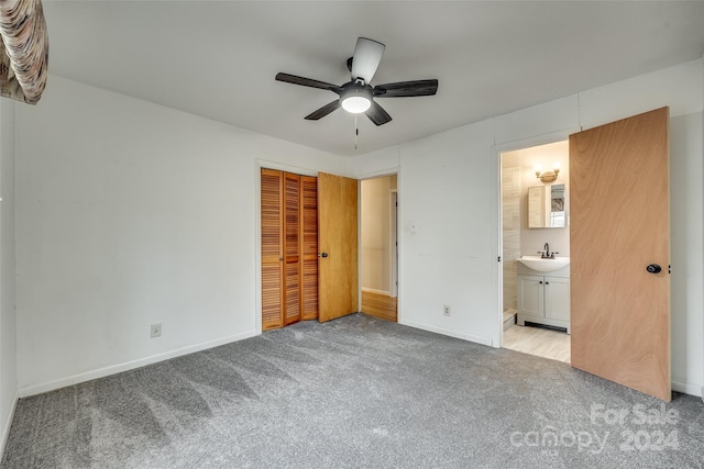 unfurnished bedroom with light carpet, ensuite bathroom, ceiling fan, sink, and a closet