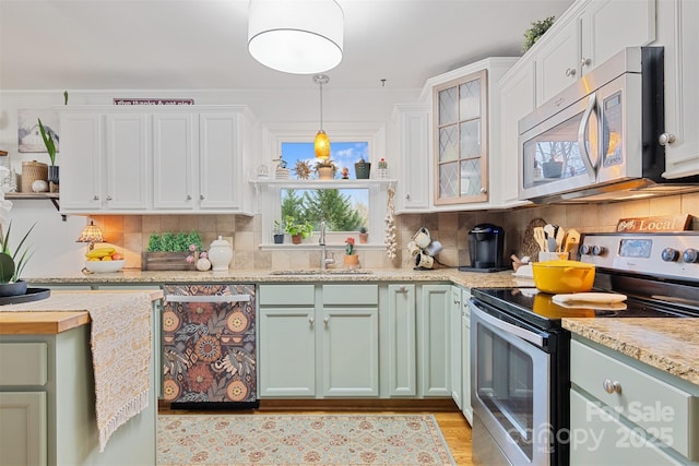 kitchen with sink, white cabinetry, hanging light fixtures, stainless steel appliances, and light stone countertops