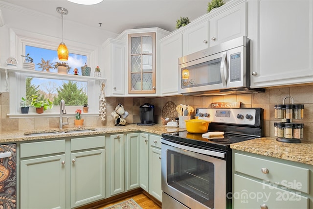 kitchen featuring sink, appliances with stainless steel finishes, white cabinetry, tasteful backsplash, and decorative light fixtures