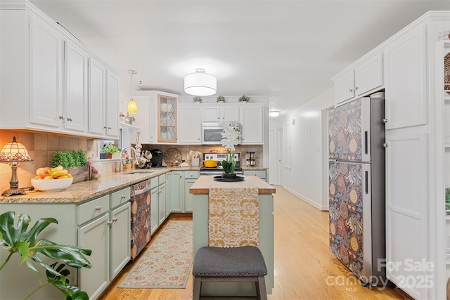 kitchen with appliances with stainless steel finishes, sink, white cabinets, green cabinetry, and light wood-type flooring