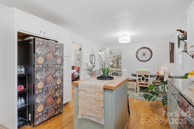 kitchen with black refrigerator, light wood-type flooring, a kitchen island, and white cabinets