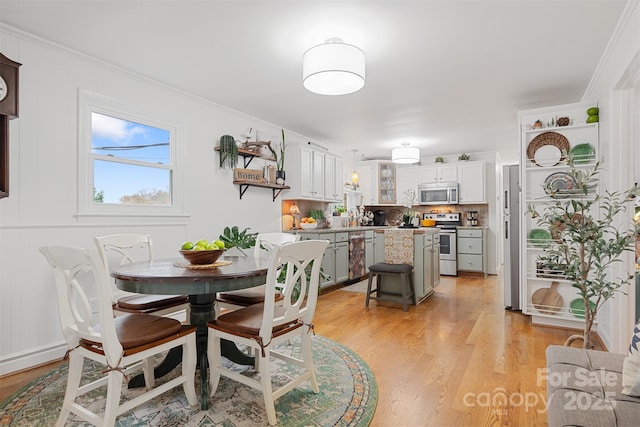 dining space with crown molding and light wood-type flooring