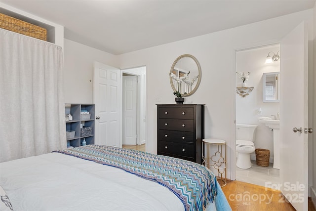 bedroom with wood-type flooring and ensuite bath