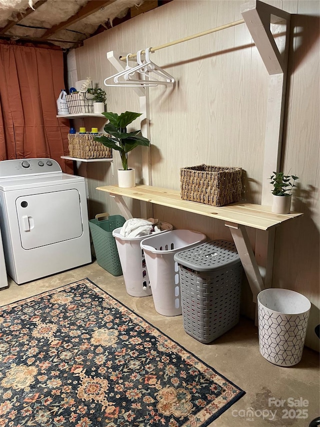 clothes washing area with washer / dryer and wood walls