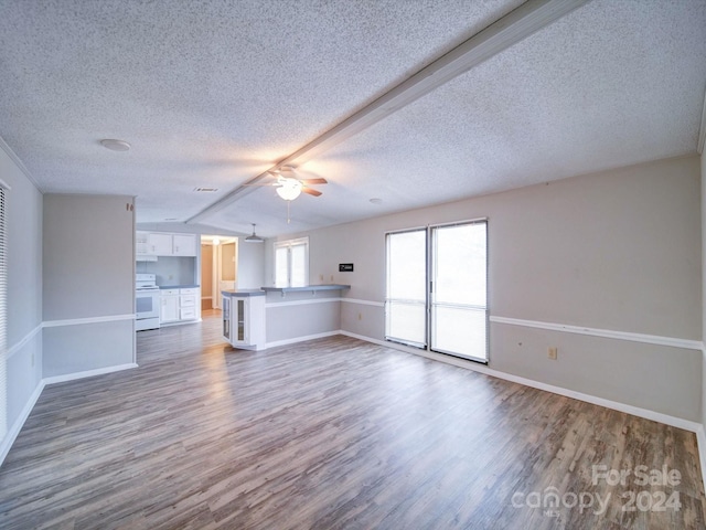 unfurnished living room featuring hardwood / wood-style floors, a textured ceiling, ceiling fan, and beam ceiling