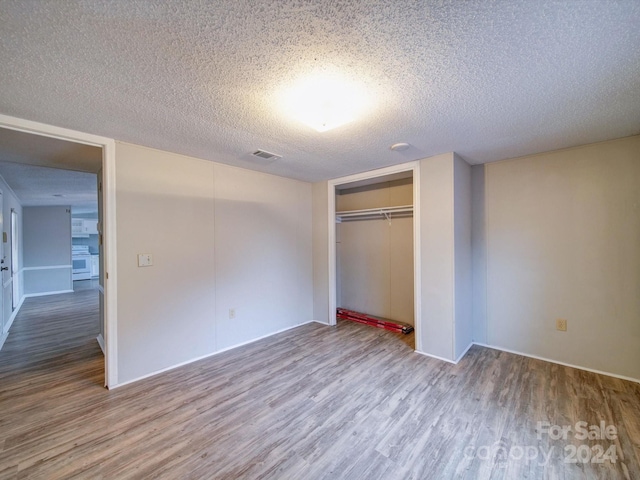 unfurnished bedroom with a closet, a textured ceiling, and hardwood / wood-style flooring