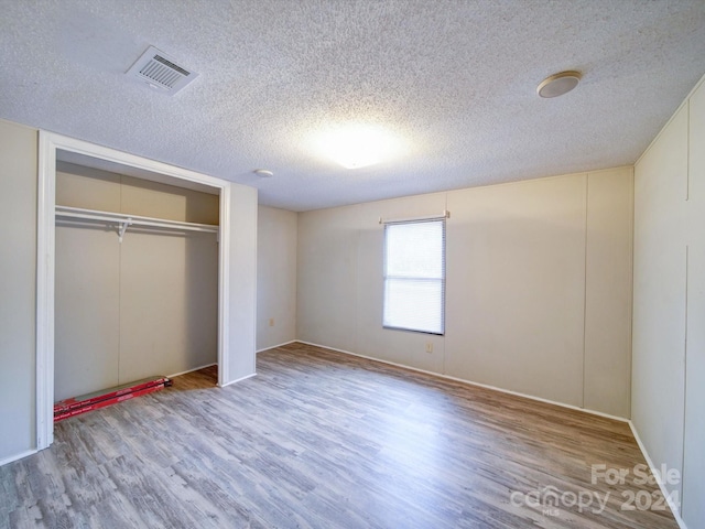 unfurnished bedroom with a closet, wood-type flooring, and a textured ceiling