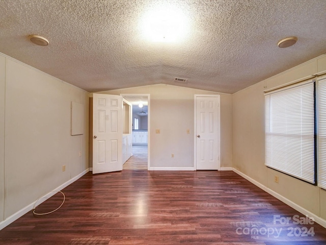 spare room with a textured ceiling, dark wood-type flooring, plenty of natural light, and lofted ceiling