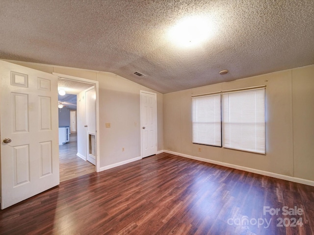 unfurnished room with a textured ceiling, ceiling fan, dark hardwood / wood-style floors, and vaulted ceiling