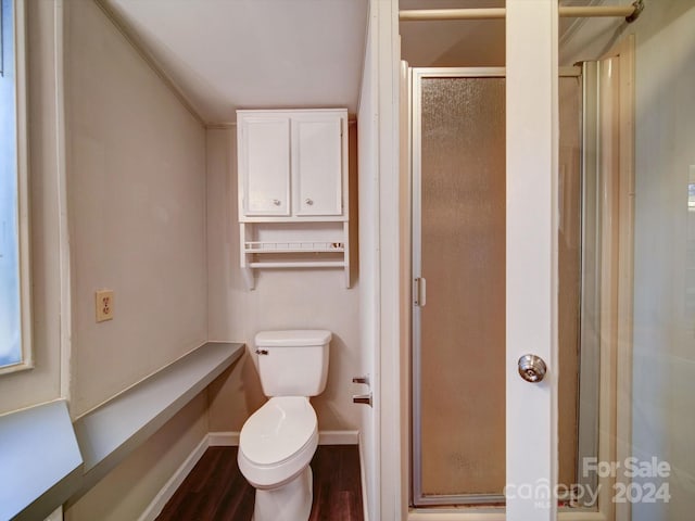 bathroom with ornamental molding, toilet, a shower with shower door, and hardwood / wood-style flooring