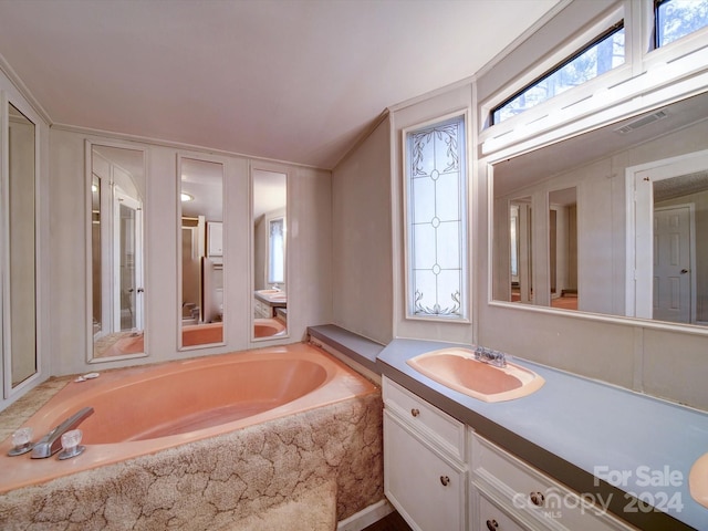 bathroom with vanity and tiled tub