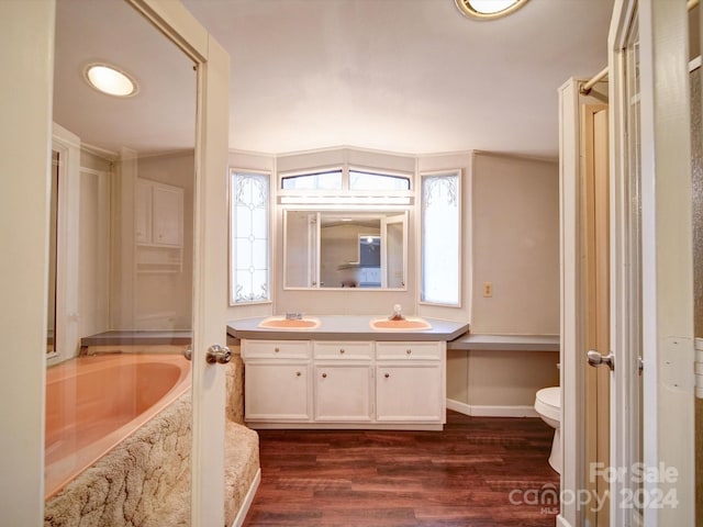 bathroom with a tub, lofted ceiling, toilet, vanity, and hardwood / wood-style flooring