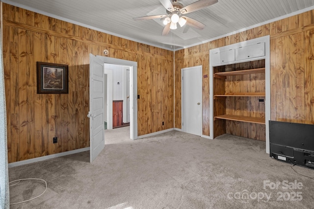 unfurnished bedroom with light carpet, wooden walls, ceiling fan, and crown molding