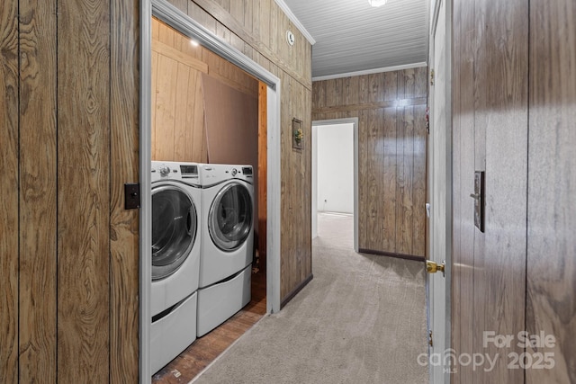 clothes washing area featuring washer and dryer, carpet flooring, crown molding, and wooden walls