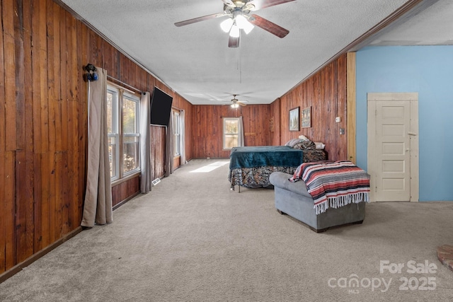 carpeted bedroom featuring ceiling fan, wood walls, crown molding, and a textured ceiling