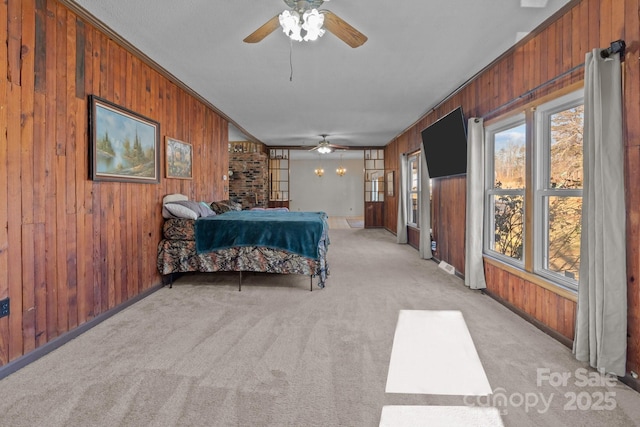 carpeted bedroom with ceiling fan, ornamental molding, and wooden walls