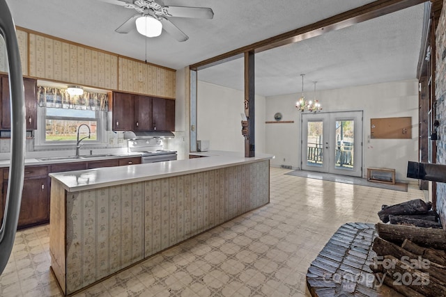 kitchen featuring french doors, ceiling fan with notable chandelier, sink, hanging light fixtures, and a kitchen island